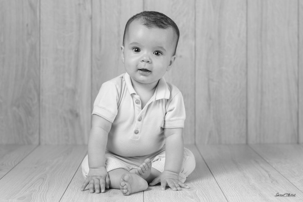 enfant assis les main au sol qui nous observe