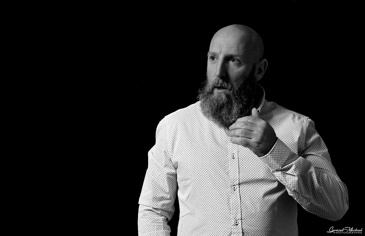 homme barbu avec une chemise blanche sur fond noir
