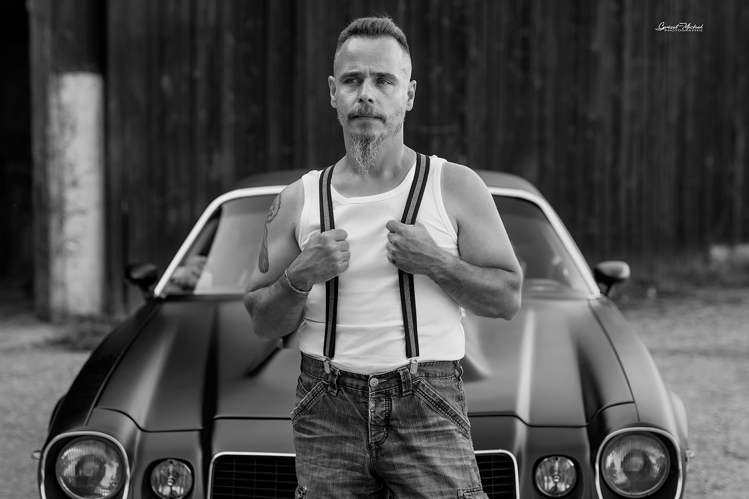 homme avec des bretelles et une camaro de 1977