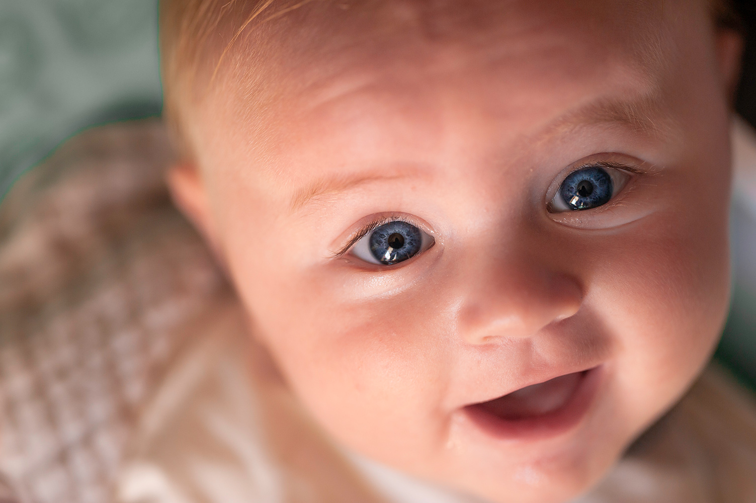un petit garcon blond au yeux bleu qui sourit devant l objectif photo