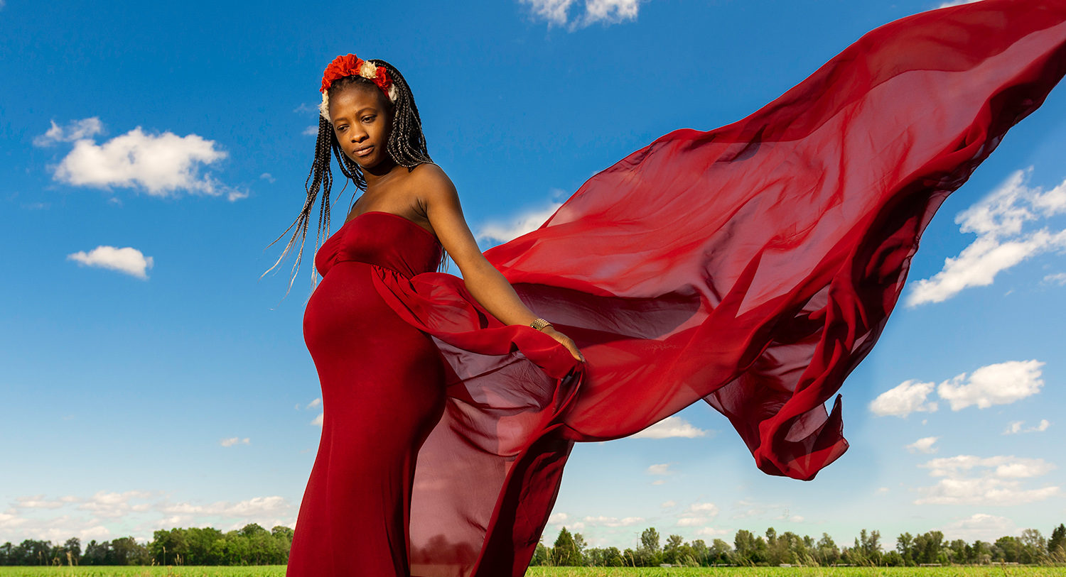une femme enceinte avec une robe rouge et un ciel bleu