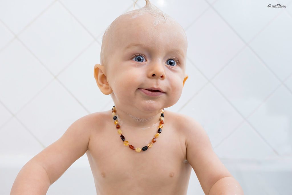 un bebe dans son bain avec un collier de pierres