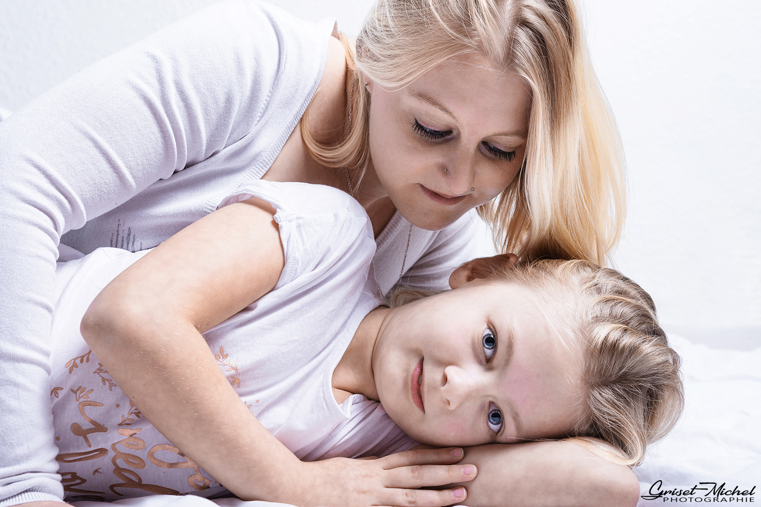 complicité une petite fille allongée qui nous regard pendant que sa maman la regard a son tour