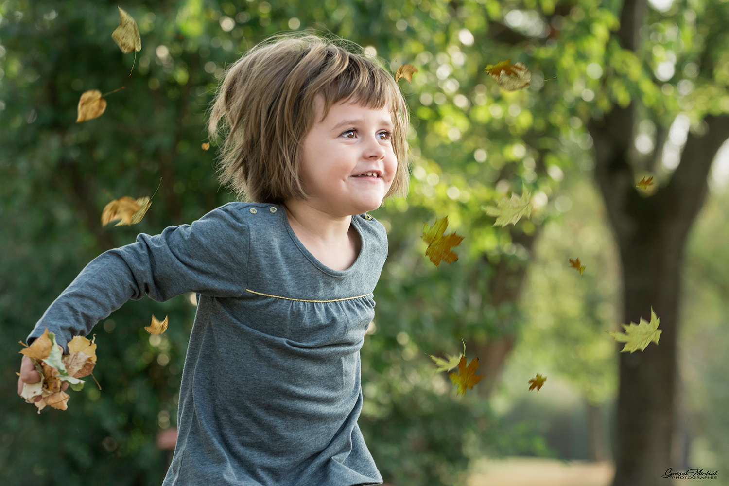 une jeune fille de 3 ans lance des feuilles en l air