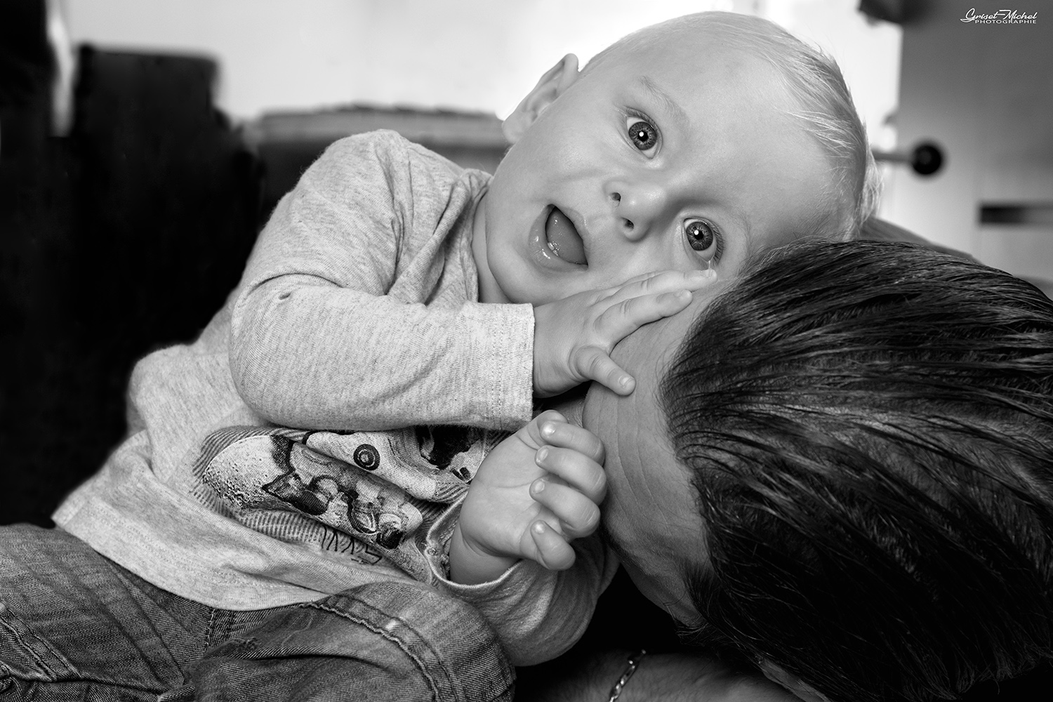 un bebe qui sourit en jouant avec son pere noir et blanc
