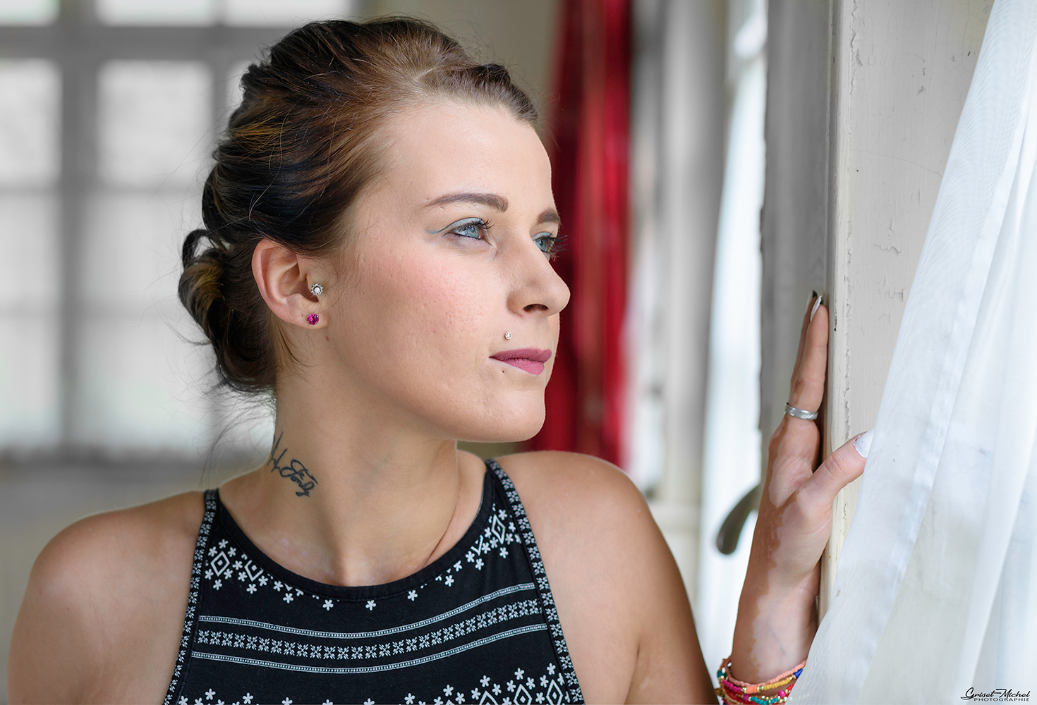 une femme avec la main posée sur un mur qui regard à la fenetre