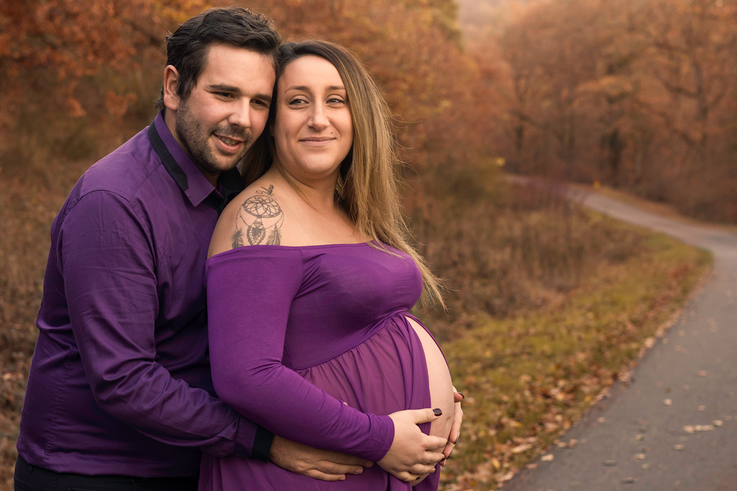 une femme enceinte fait un calin a son mari dans un decor automnal