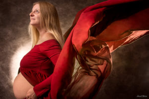 une femme enceinte dans un studio photo a selestat avec une robe rouge