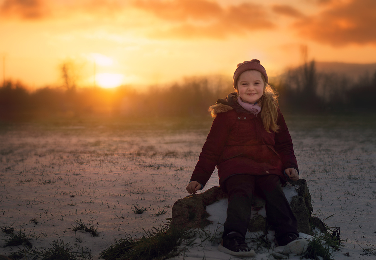 une ptite fille dans la neige avec un super coucher du soleil