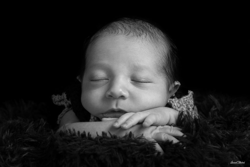 un bebe les main croise qui dort photo en noir et blanc