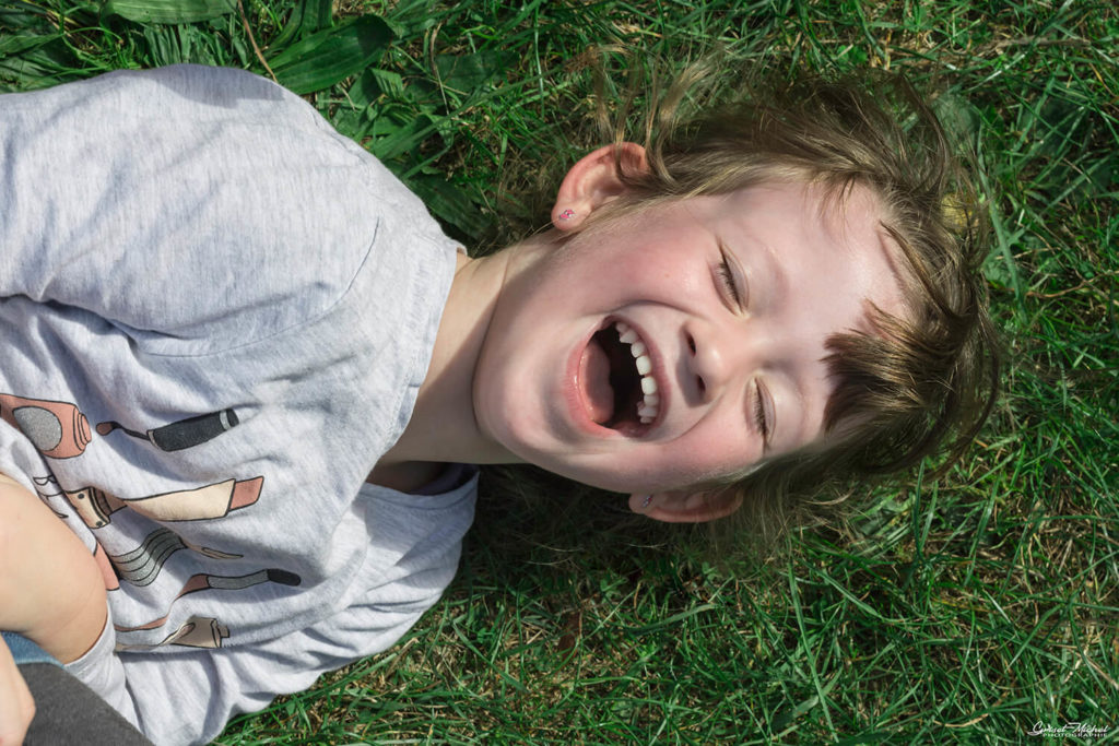petite fille qui rigole dans l'herbe