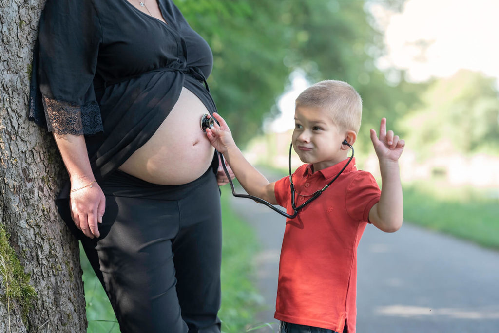 Seance grossesse un petit garcon met un stethoscope contre le ventre de sa maman