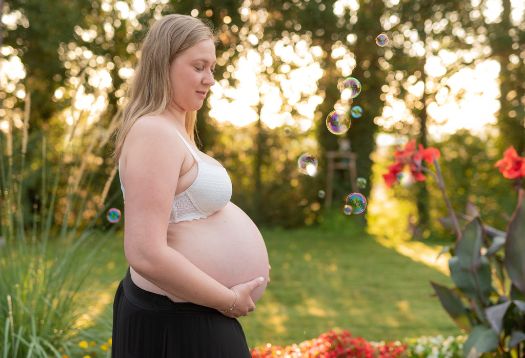 une femme enceinte en fin de grossesse pendant une seance photo dans un jardin en alsace