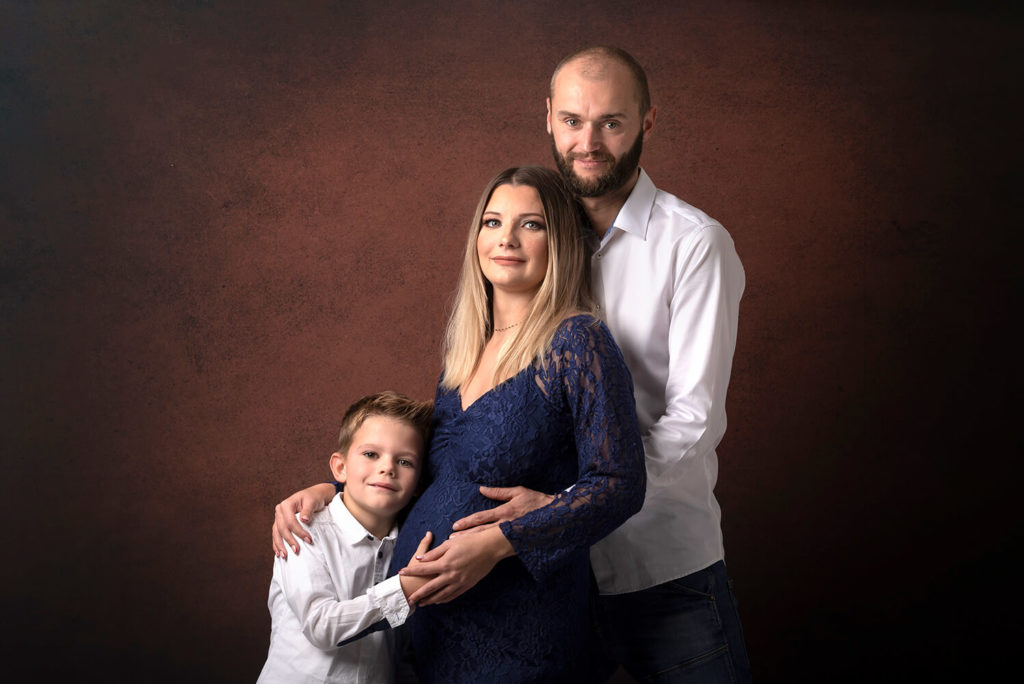 une belle famille en shooting photo de studio pour réaliser une séance grossesse