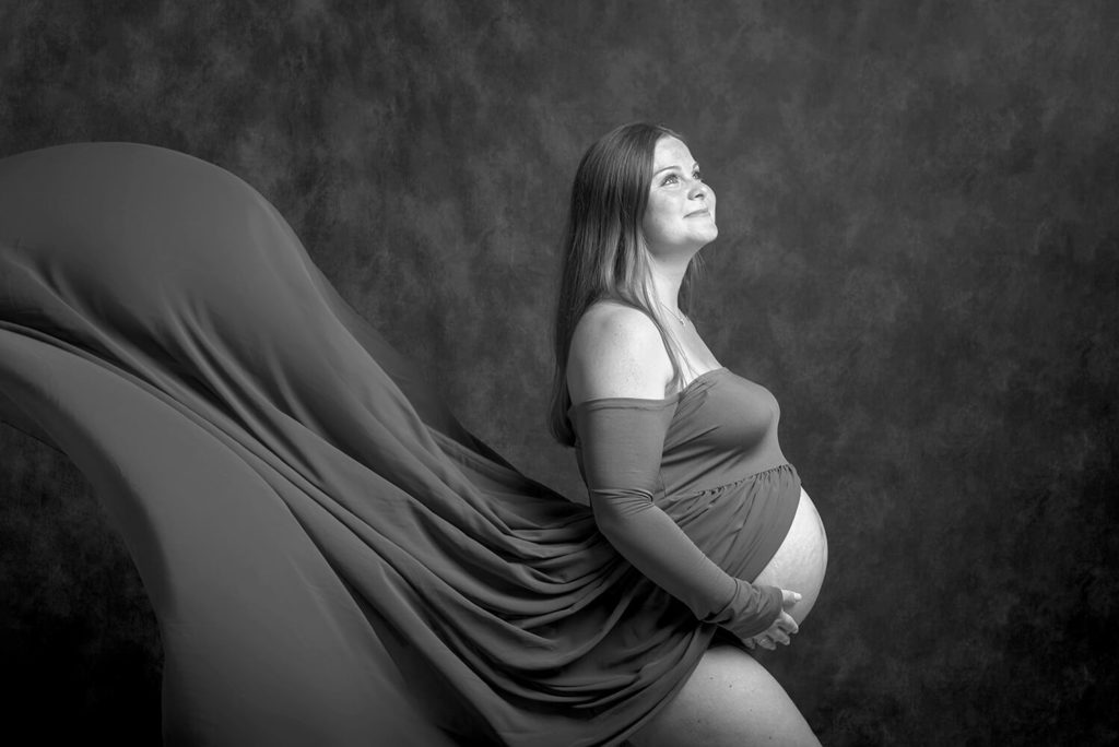une future maman en shooting photo en noir et blanc avec une robe qui vole