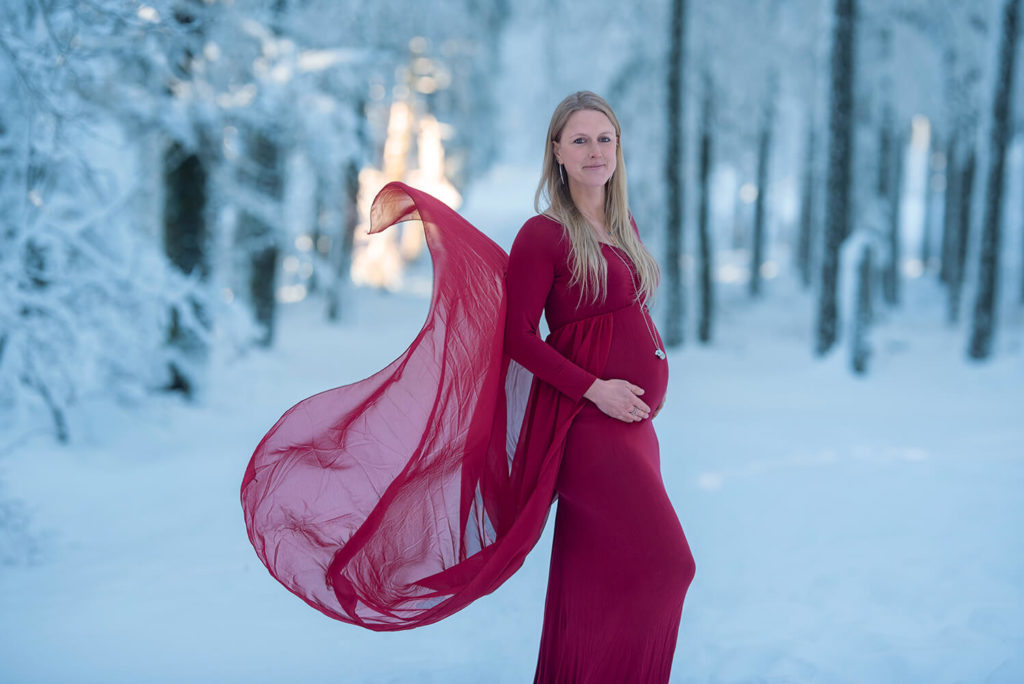 une femme blonde avec une robe rouge enceinte a la neige au champs du feu