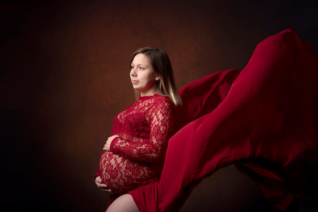 une femme enceinte avec une belle robe rouge qui vole dans les air chez griset michel photographe à Sélestat
