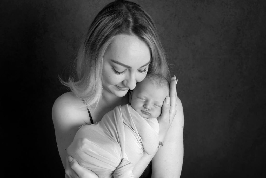 une maman tiens sa petite fille dans ses bras en lui faisait un câlin photo en noir et blanc