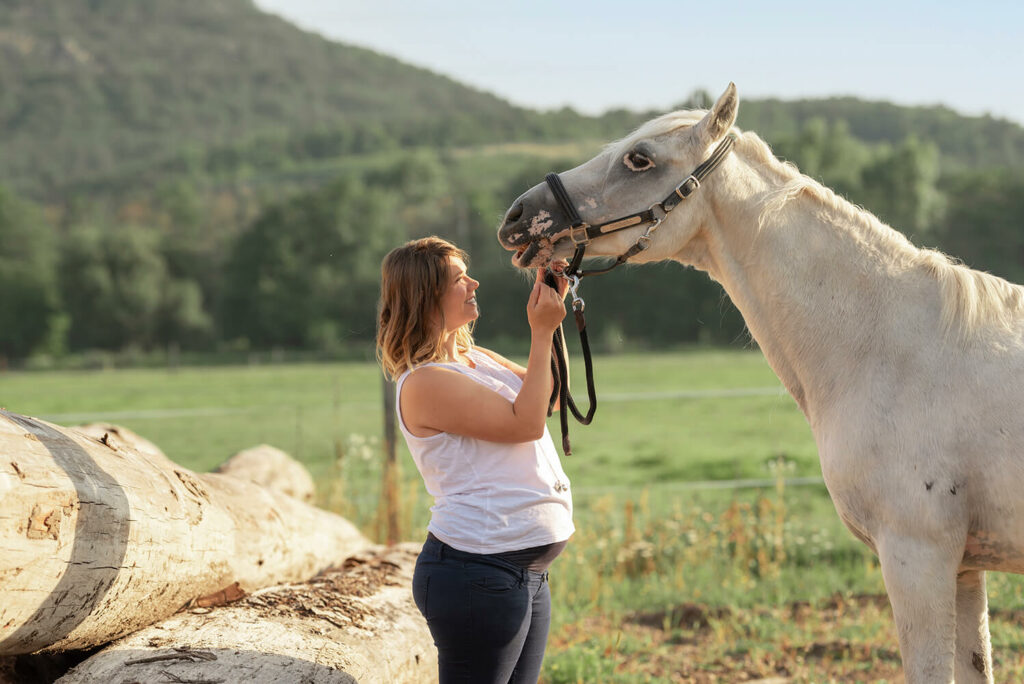 Future maman enceinte caressant son cheval dans une écurie à Chatenois