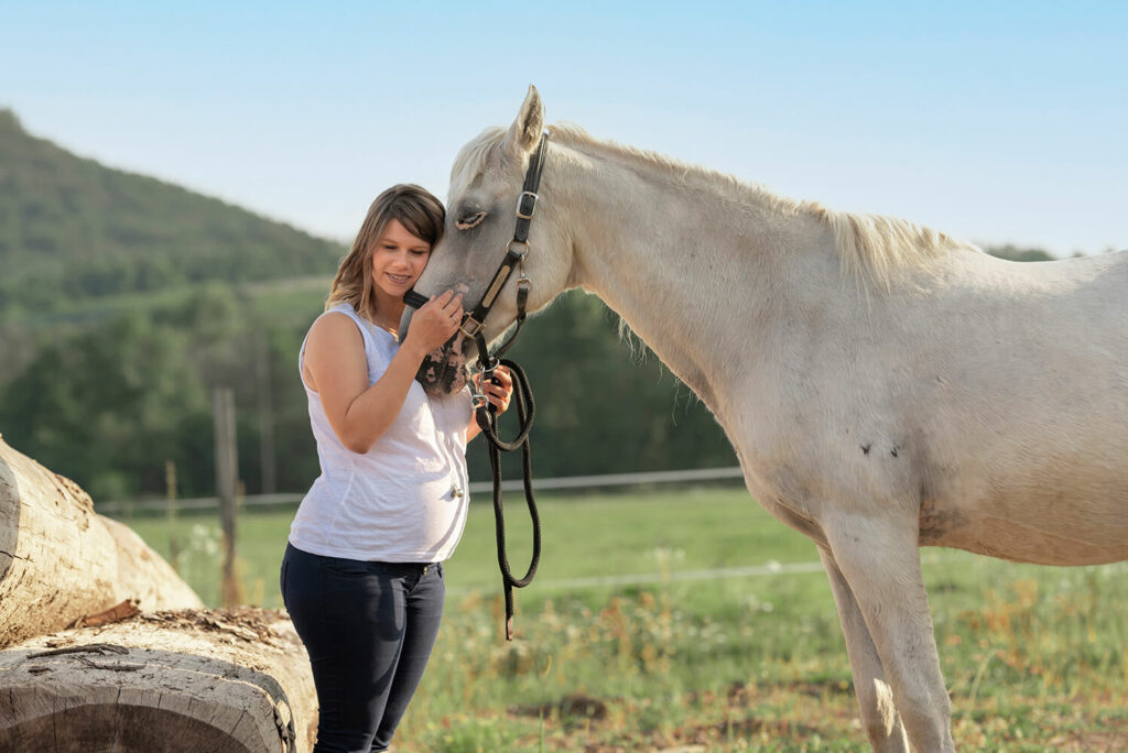 Moment de tendresse partagé entre une future maman et son cheval dans une écurie à Chatenois